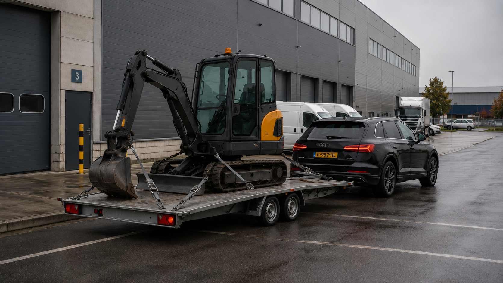 Audi met aanhanger en graafmachine
